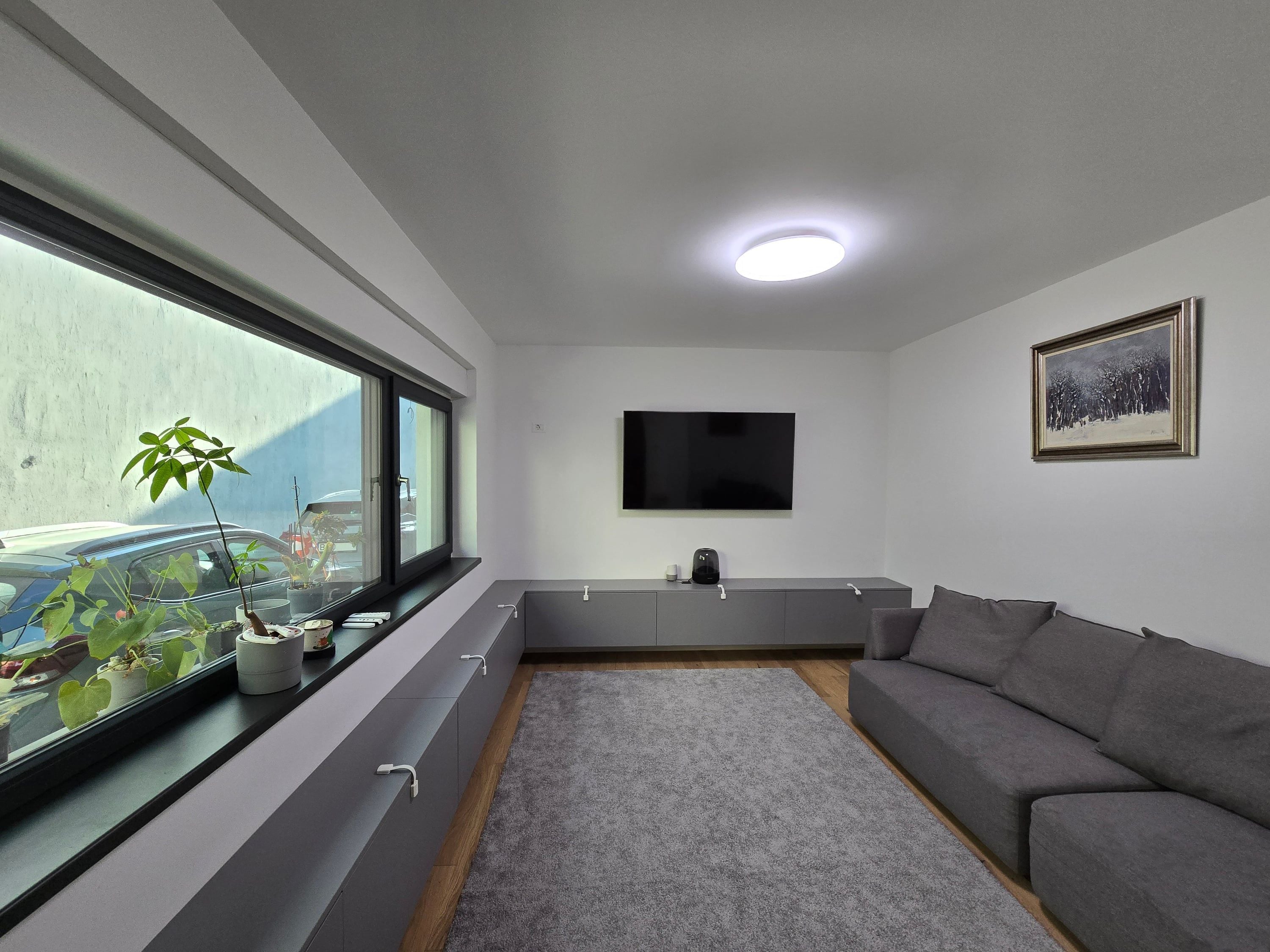 Living unitate 1 — sofa gri, panou de lemn lamelar și acces spre bucătărie