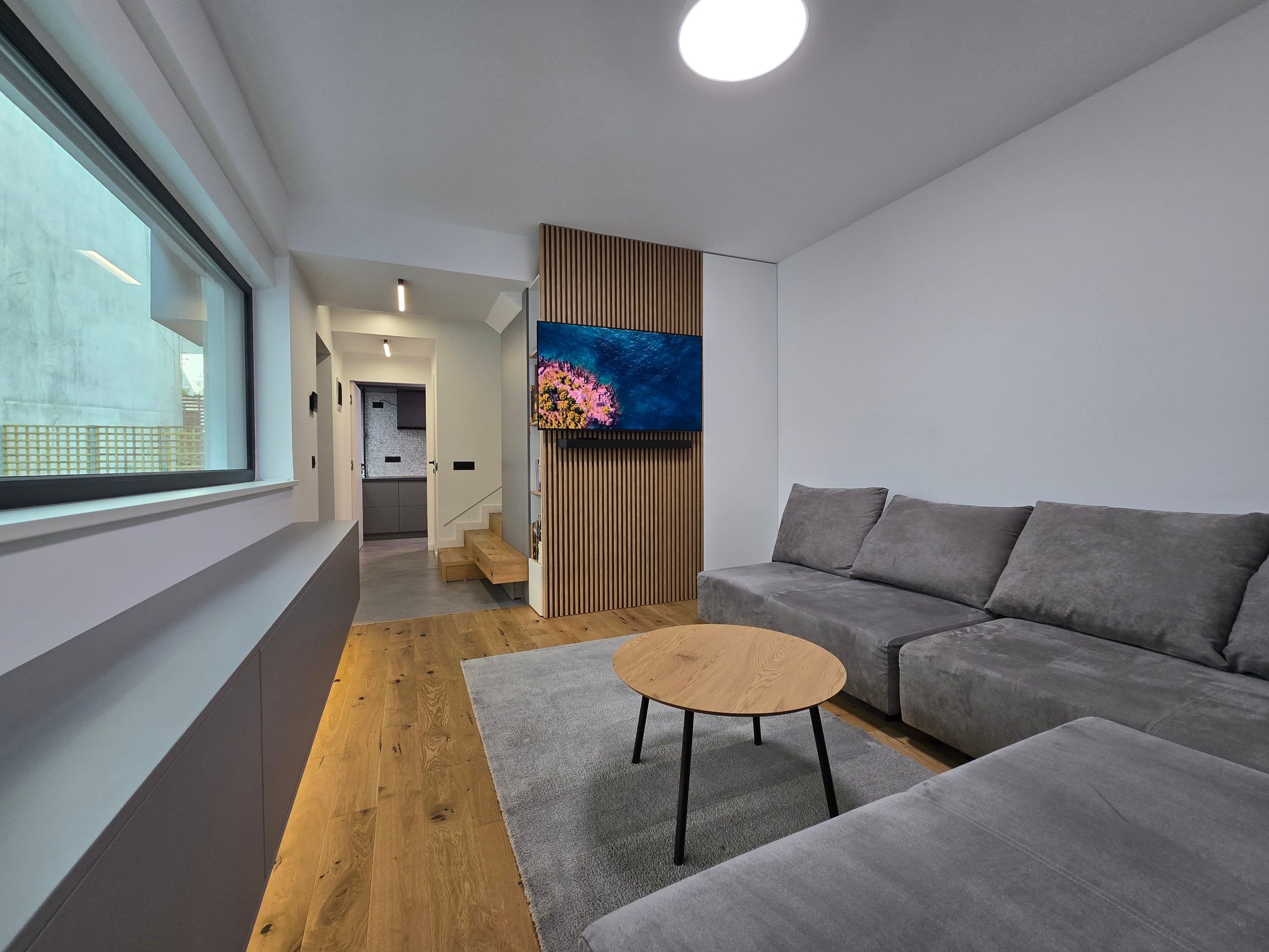 Living unitate 2 — sofa gri și fereastră largă spre stradă